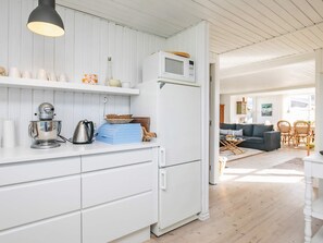 Una cocina moderna con armarios blancos, una batidora de pie y un microondas.