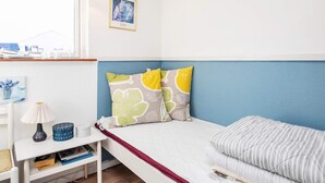 A bedroom with a bed, a bedside table, a lamp, a picture frame, and a window with a view.