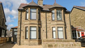 A stone building with a corner turret and bay windows. - By the Tracks (Buxton)