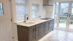 A modern kitchen with a large island, white countertops, and grey cabinets. - By the Tracks (Buxton)