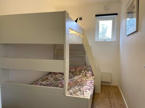 A bunk bed with a floral bedspread, a window with a view of trees, and a light fixture on the wall. - 4 Star Holiday Home in Lottorp (Löttorp)