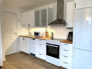 Una cocina moderna con armarios blancos, microondas, cafetera y horno.