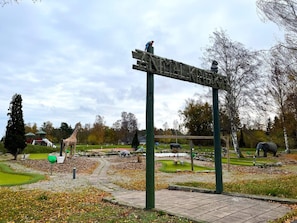 A park with a wooden sign, a giraffe, and an elephant enclosure. - 4 Star Holiday Home in Lottorp (Löttorp)