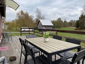 Relax on the outdoor patio with a table and chairs, surrounded by a serene natural setting.