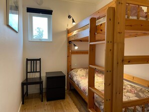 A bunk bed with a desk and chair, a window, and a lamp.