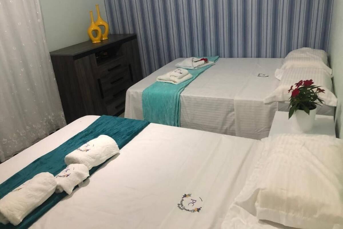 A hotel room with two beds, a small desk, and a potted plant.