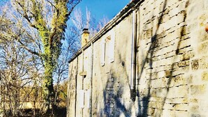 A narrow alleyway with a weathered stone building on one side.