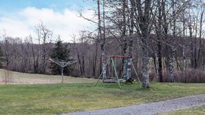 En park med en grussti, gyngestativ og nøgne træer.