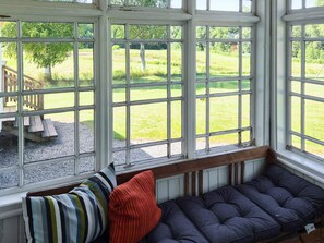 A room with a bench and a view of a grassy outdoor area through large windows. - 11 Person Holiday Home in Hogsater (Högsäter)