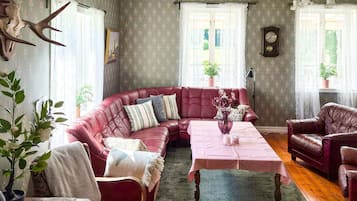 Una habitación con un sofá de cuero rojo, una mesa con un florero y un reloj en la pared.