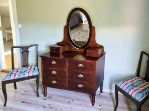 A wooden dresser with a mirror, two upholstered chairs, and a patterned rug on the floor. - 11 Person Holiday Home in Hogsater (Högsäter)