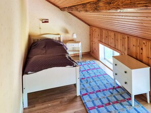 A bedroom with a bed, a nightstand, a dresser, a window, and a wooden ceiling. - 11 Person Holiday Home in Hogsater (Högsäter)