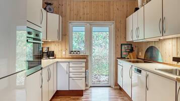 A modern kitchen with wooden walls, white cabinets, and a central island.