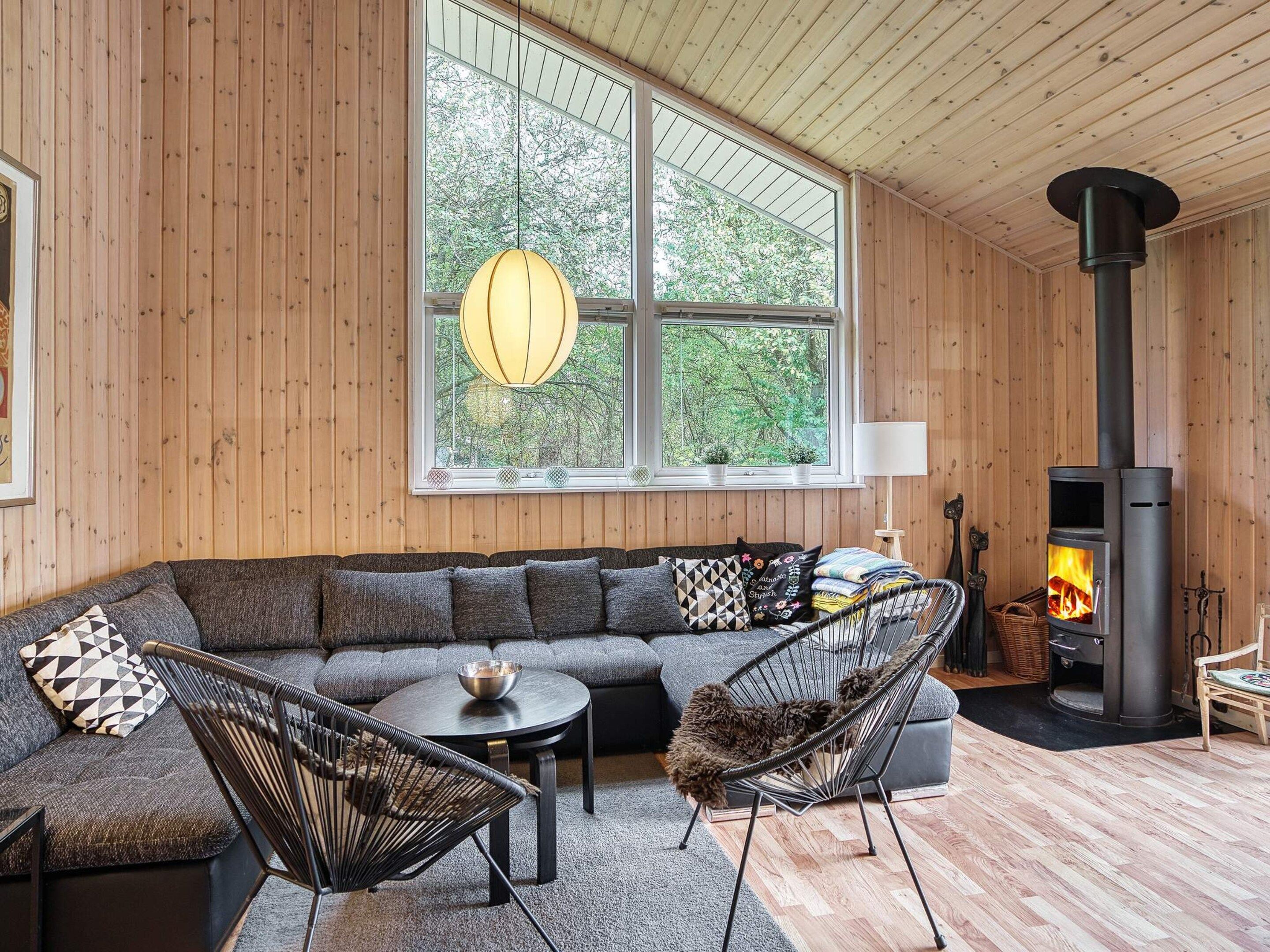 Ett mysigt vardagsrum med ett stort fönster, en öppen spis, en soffa och en fåtölj.