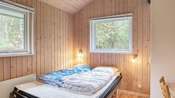 A bedroom with a bed, two windows, and a wooden ceiling.