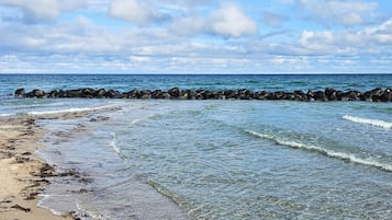 A beach with clear water, a rocky breakwater, and a sandy shore.