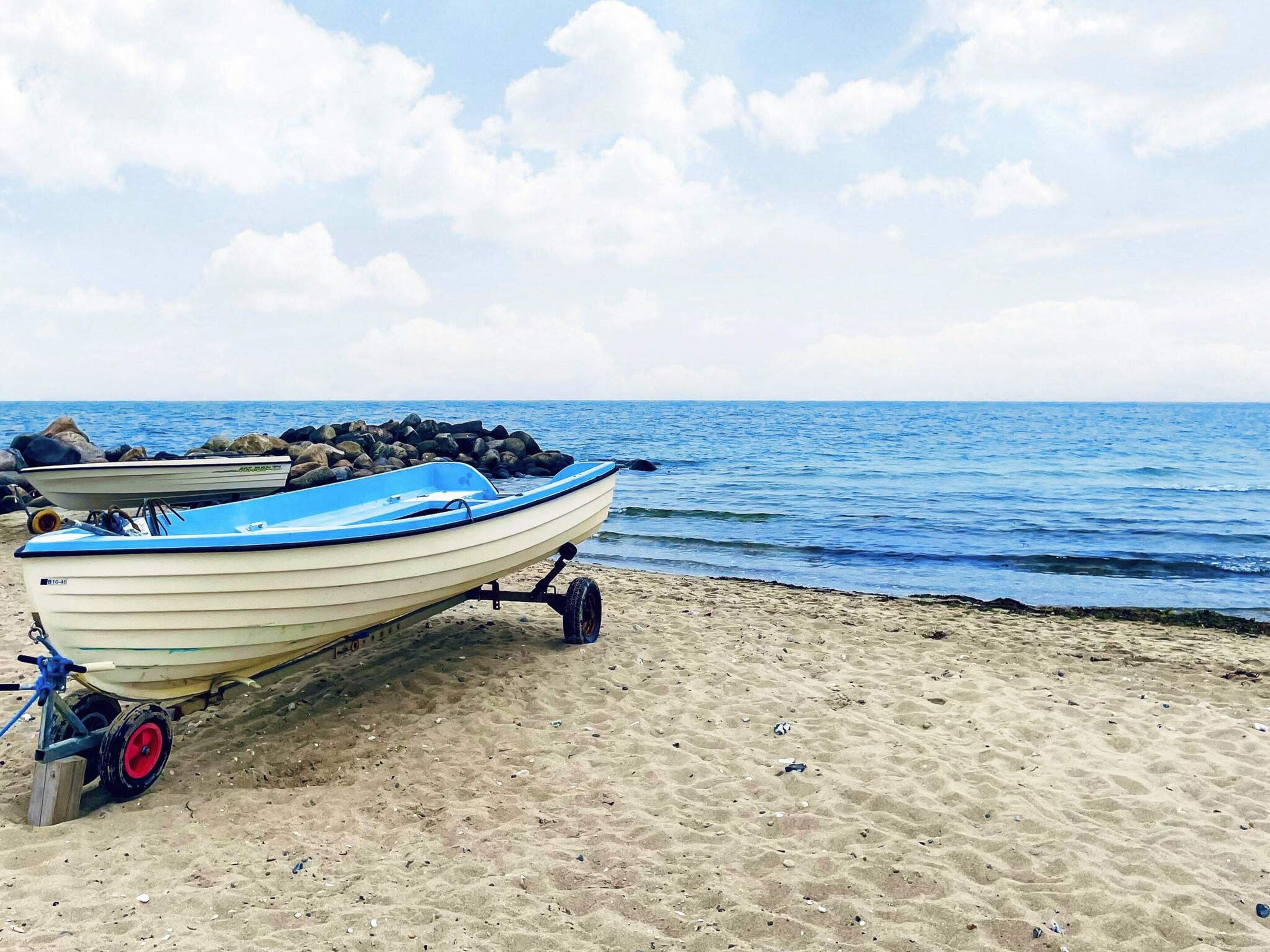 A boat on a sandy beach with the ocean in the background.