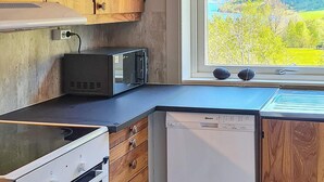 Una cocina compacta con microondas, lavavajillas y armarios de madera.