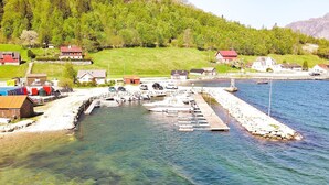 Un puerto deportivo con barcos amarrados, rodeado de casas y una ladera cubierta de bosque.