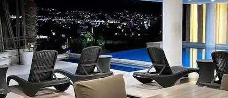 A modern outdoor dining area with a pool and city view.