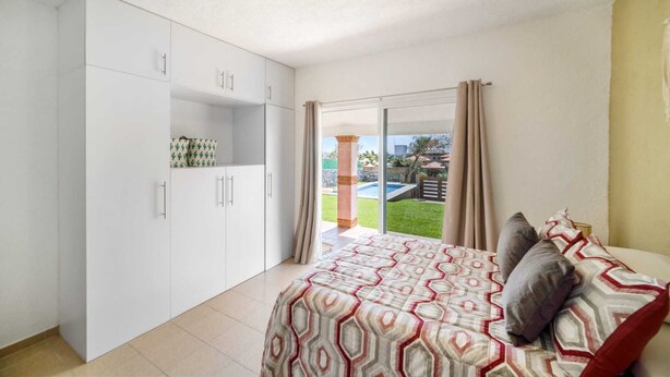 A bedroom with a bed, a wardrobe, and a sliding glass door leading to a balcony.