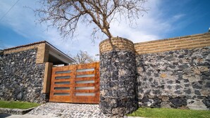 A stone wall with a wooden gate and a tree in front.