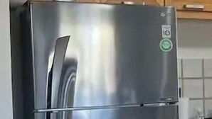 A stainless steel refrigerator in a kitchen with wooden cabinets and a tiled floor. - Casas TZL (Cabo San Lucas)