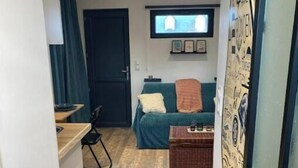 Un pasillo estrecho que conduce a un dormitorio con una cama, un televisor y un reloj de pared.