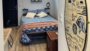 Un dormitorio con cama, ventana, una tabla de surf y una puerta.