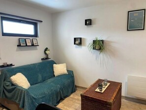 A living room with a teal sofa, a wooden coffee table, and a potted plant.