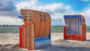Deux cabanes de plage, portant les numéros 23 et 24, une plage de sable et la mer en arrière-plan.