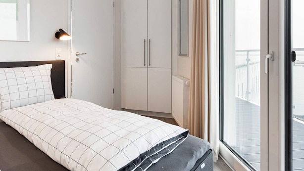 Une chambre à coucher avec un lit, une armoire, un radiateur et une fenêtre avec des rideaux.