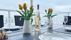 Une table dressée pour le dîner, avec de l’argenterie, des assiettes blanches et des vases ornés de tulipes jaunes.