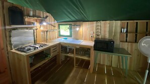 Een kleine keuken met een gasfornuis, een magnetron en een spoelbak.
