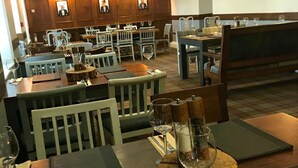 Un restaurante con mesas y sillas de madera, copas de vino y menús.