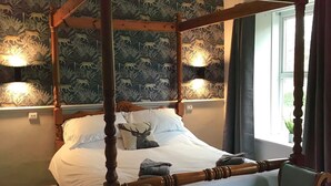 Una cama con dosel, un banco y un aplique de pared.