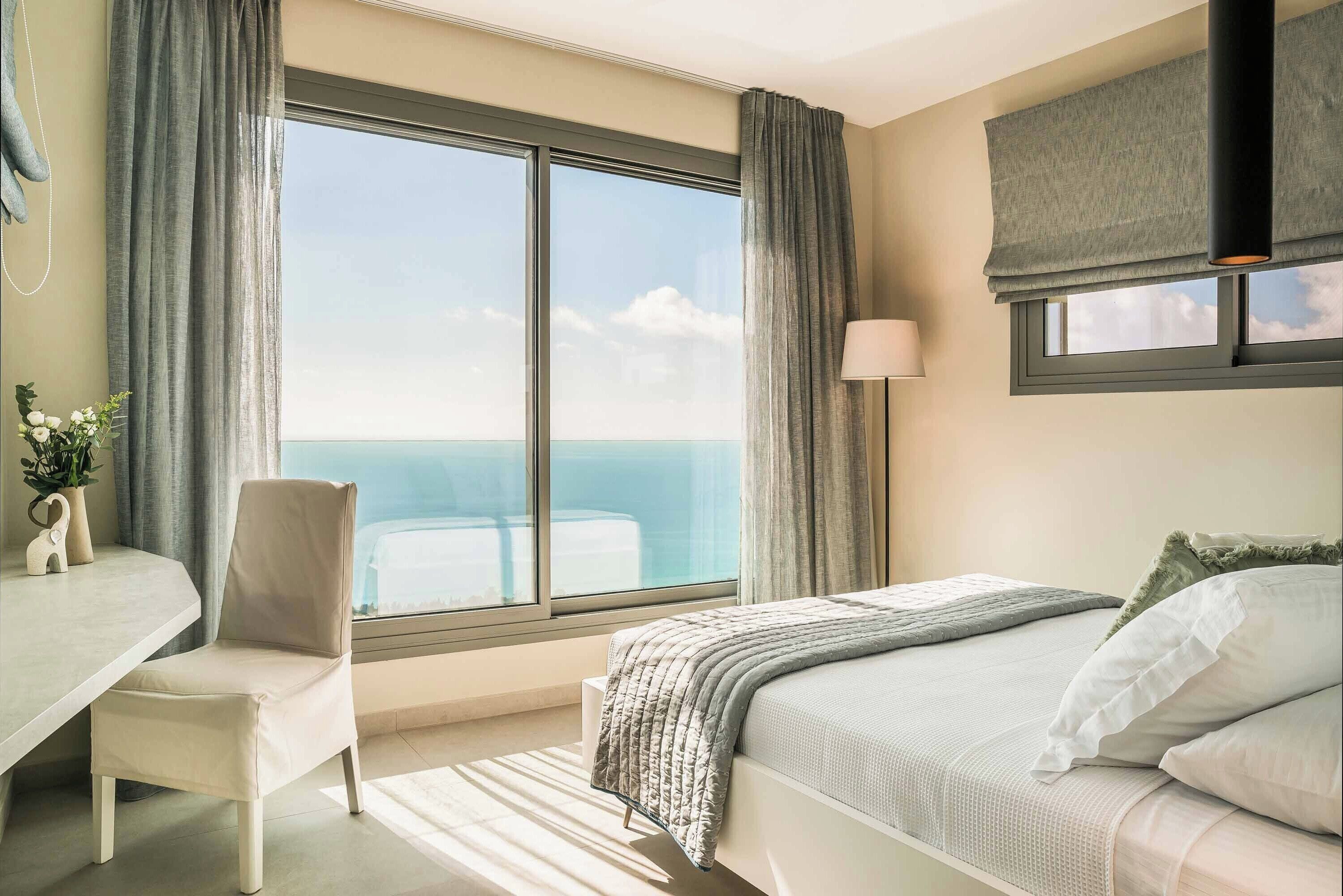 Een hotelkamer met een groot raam, een bed, een stoel en een bureau.
