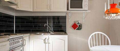 A kitchen with white cabinets, a microwave, a clock, and a chandelier.