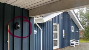 Un edificio con puerta, ventana y un pequeño espacio exterior con un banco.