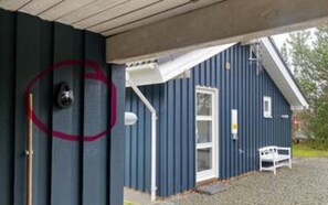 A building with a door, a window, and a small outdoor area with a bench.