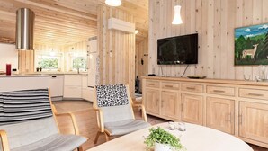 Una cocina moderna con armarios de madera, un televisor grande y una zona de comedor con mesa y sillas.