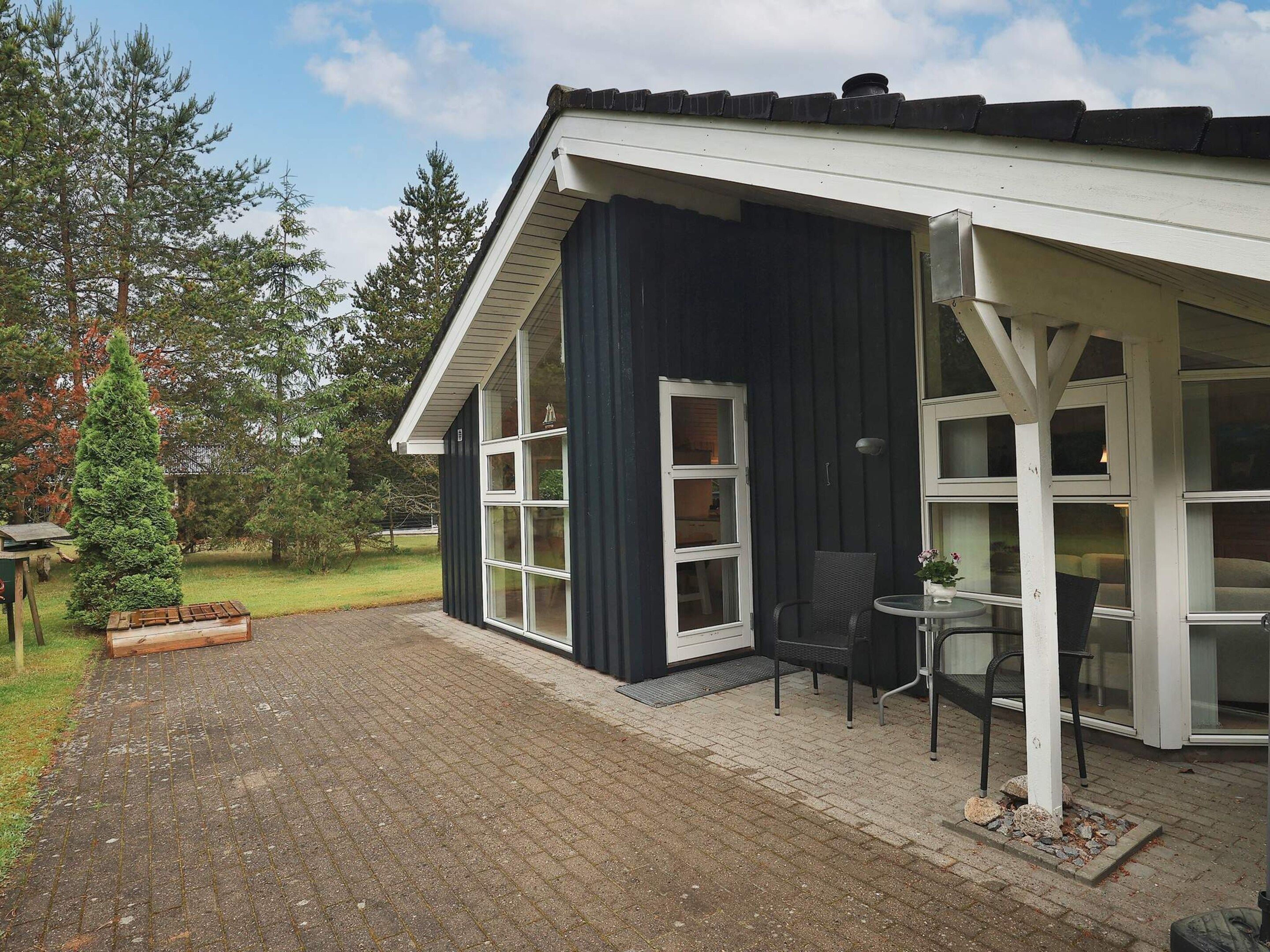 A building with a dark exterior, white trim, and a covered patio area with a table and chairs.