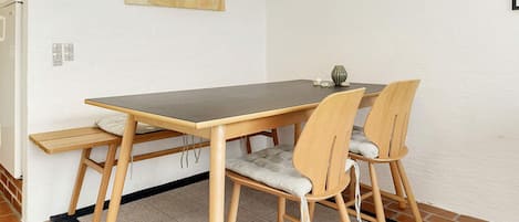 A dining area with a table, chairs, a pendant light, and a rug.