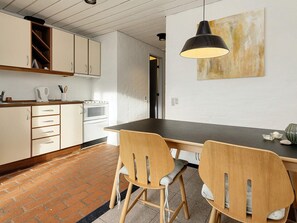 A kitchen with white cabinets, a black pendant light, and a brick floor. - 4 Person Holiday Home in Brovst (Brovst)