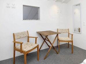 A room with two wooden chairs, a small table, a window, and a mirror on the wall. - 4 Person Holiday Home in Brovst (Brovst)