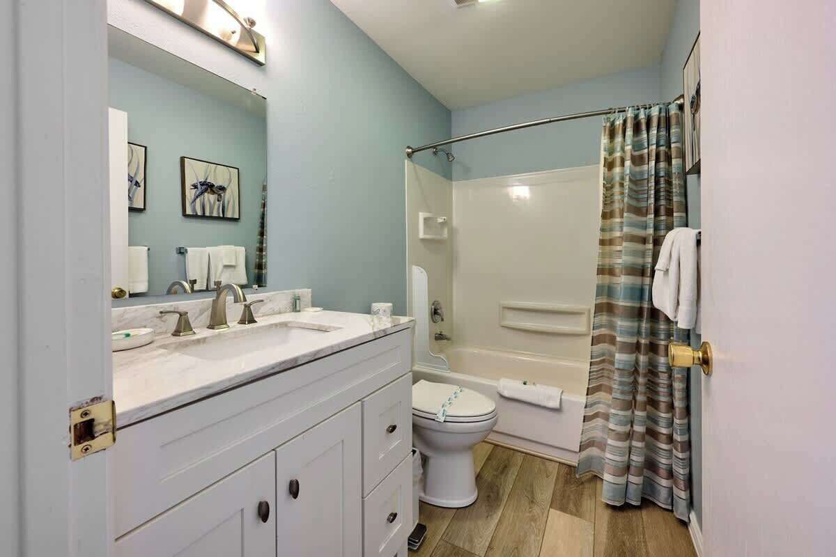 A bathroom with a double sink vanity, a toilet, a shower area, and a glass-enclosed shower.