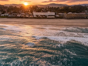 A coastal hotel with multiple buildings, a beach, and waves.