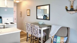 A compact kitchen with a dining area, a white stove, and a table with patterned chairs. - Cozy Ocean View Condo - Ground Floor - Fireplace! (Lincoln City)
