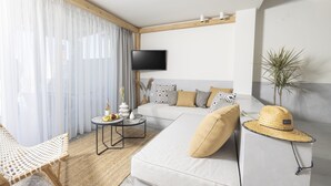 A modern living room with a sofa, a coffee table, a TV, and a plant. - Kaktus Suites Private Pool (Kassandra)