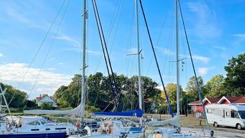 Un puerto deportivo con varios veleros amarrados, un remolque y un edificio al fondo.